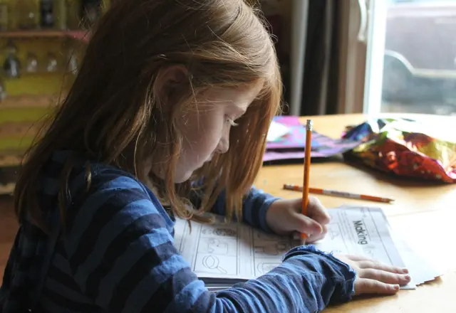 Girl working on an activity page at the kitchen table