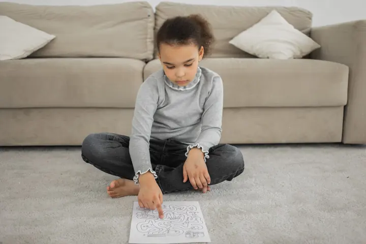 Girl sitting on the floor solving a maze page